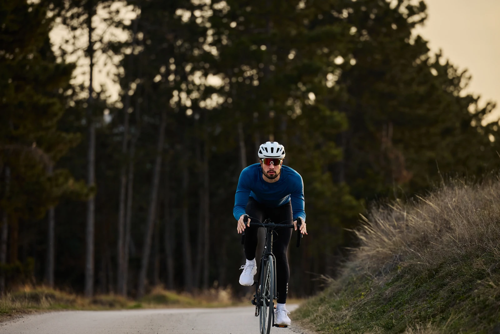 Road cyclist wearing a blue jersey on a forest road