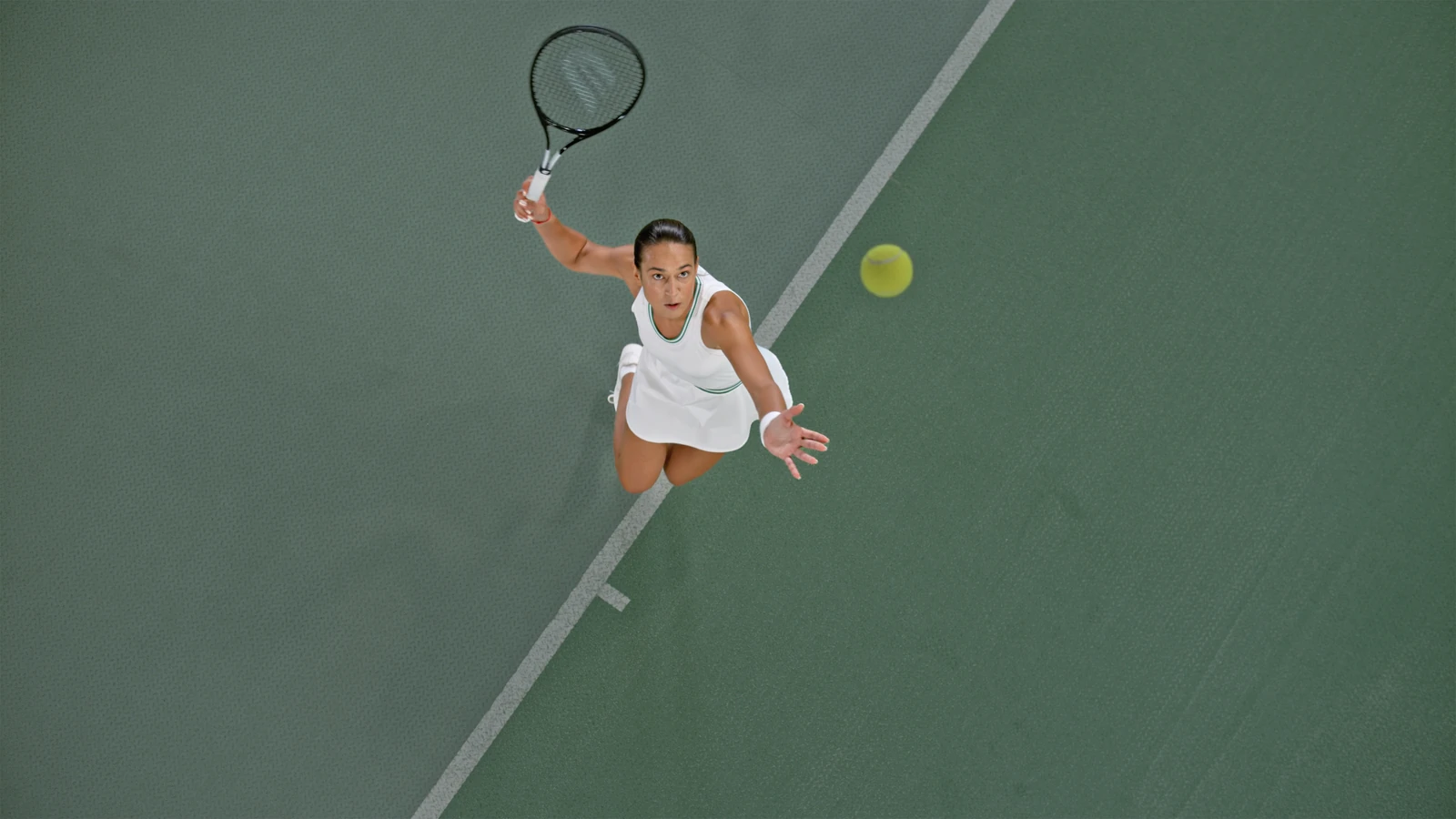 Overhead view of a woman reaching for a tennis ball on court